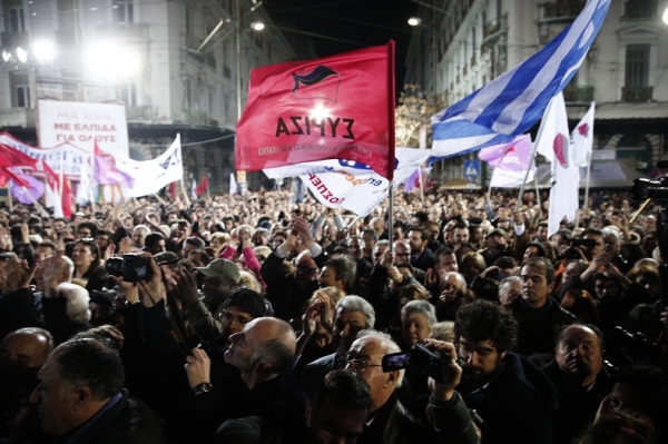 A supporter of radical left Syriza party waves party flag as opposition leader and head of the party Alexis Tsipras delivers speech during a campaign rally in central Athens
